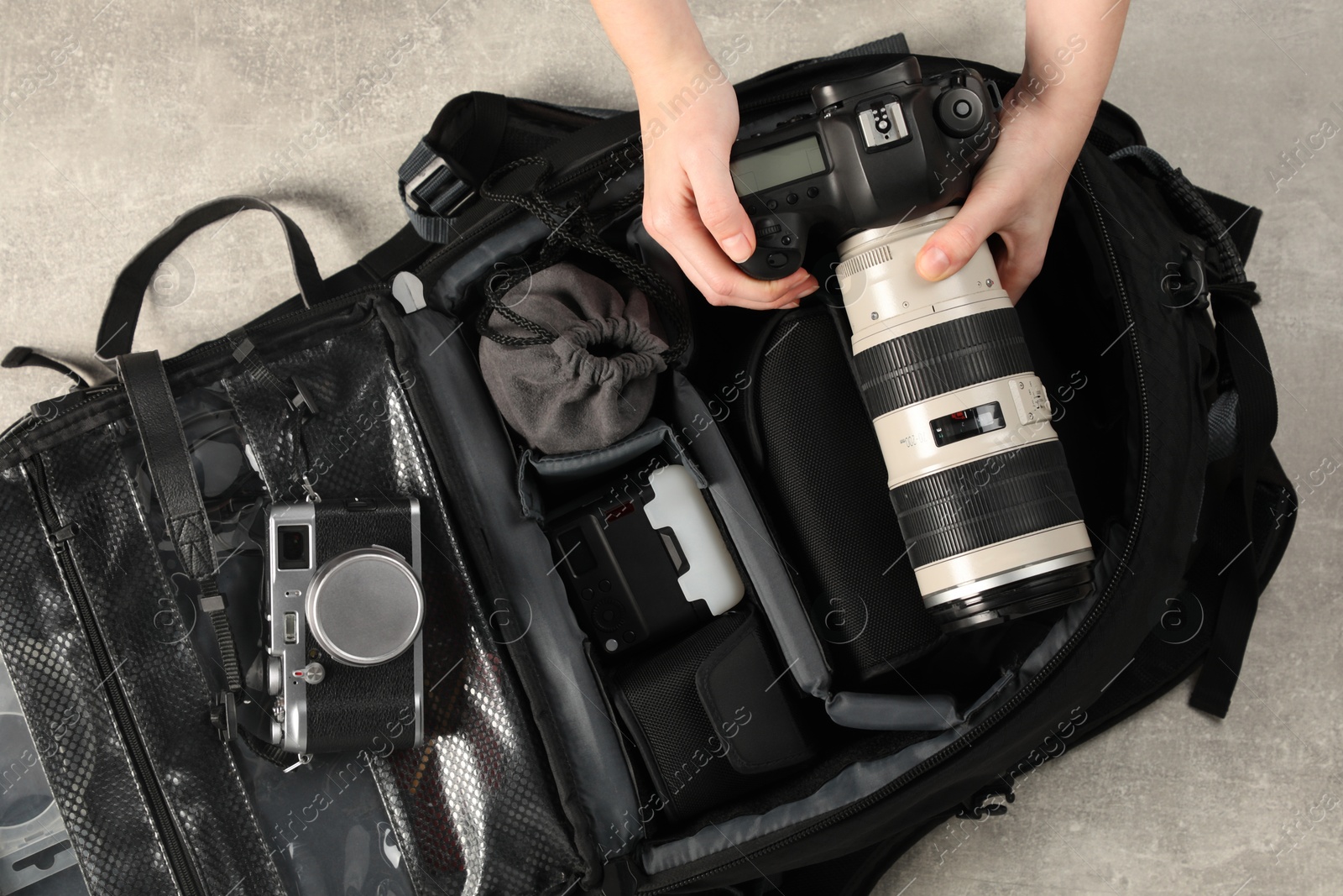 Photo of Photographer with professional equipment and backpack at light table, top view