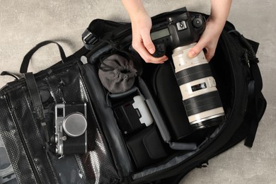 Photographer with professional equipment and backpack at light table, top view