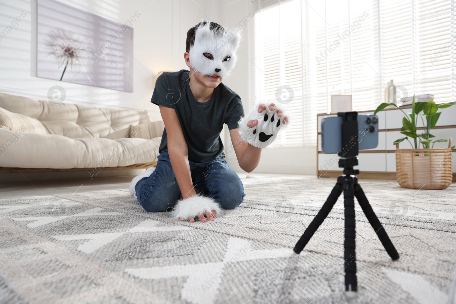 Photo of Quadrobics. Boy in cat mask and gloves recording video at home