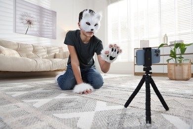 Quadrobics. Boy in cat mask and gloves recording video at home