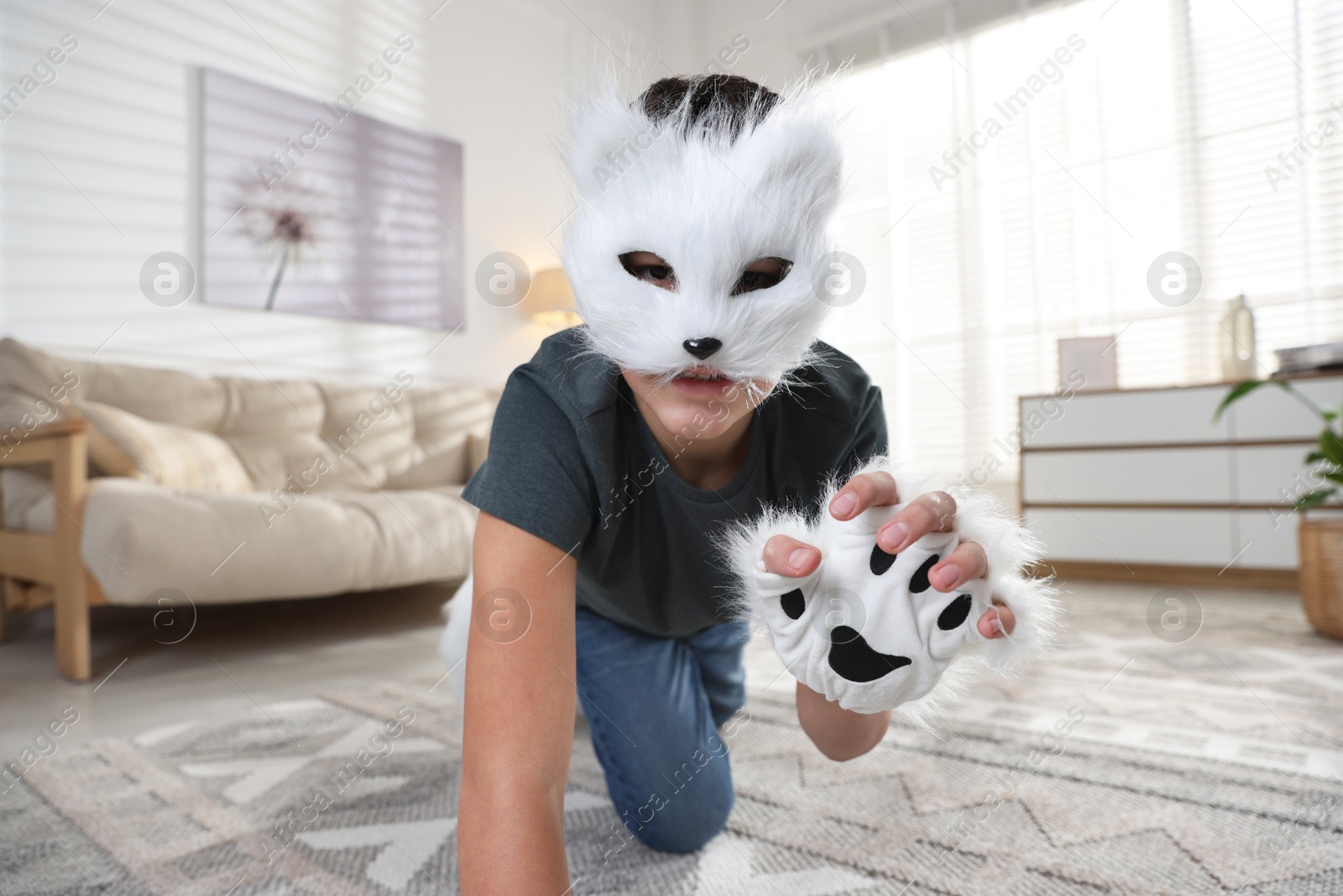 Photo of Quadrobics. Boy wearing cat mask and gloves on floor at home