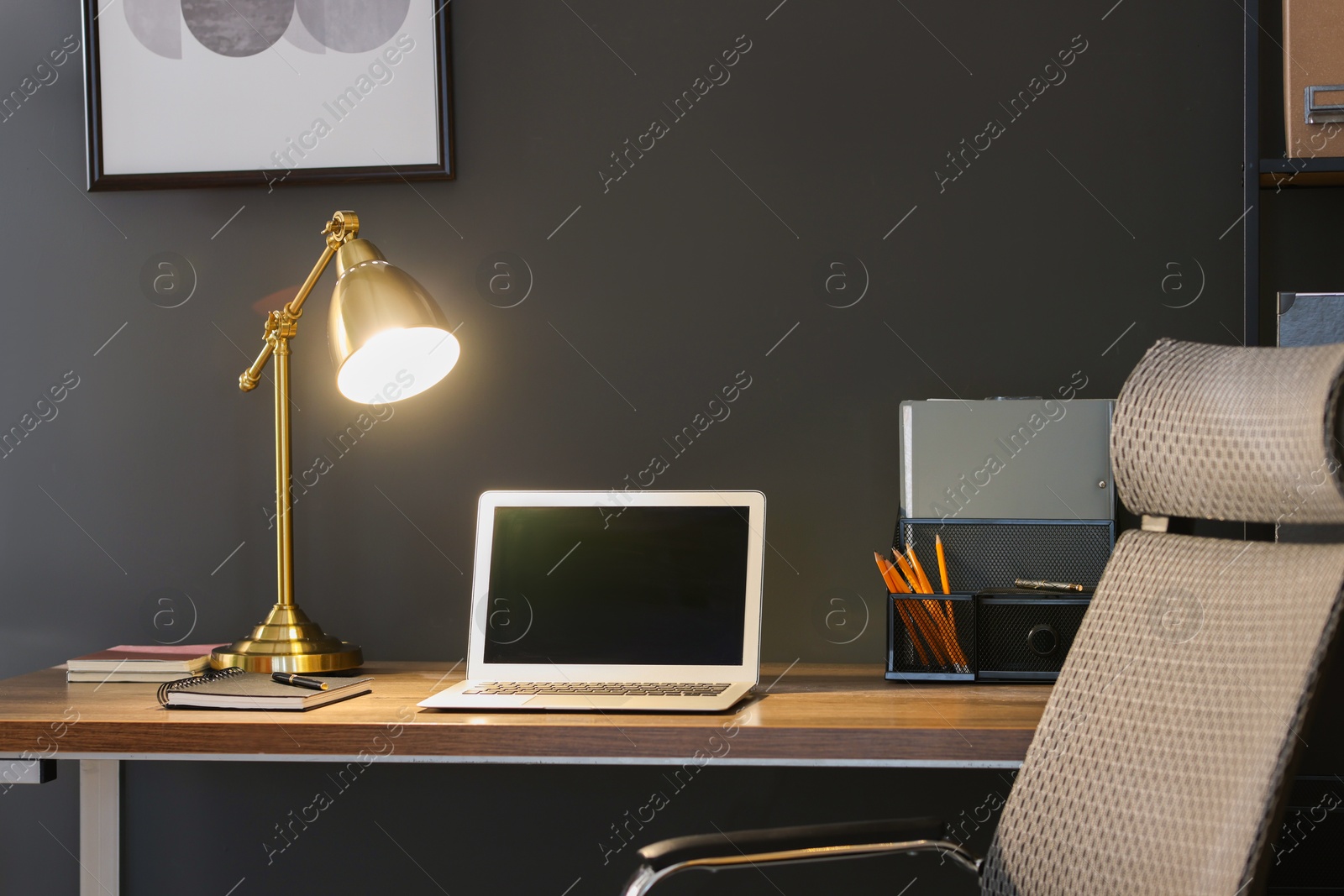 Home office. Comfortable workplace with laptop and lamp on wooden desk in room Photo of Home office. Comfortable workplace with laptop and lamp on wooden desk in room