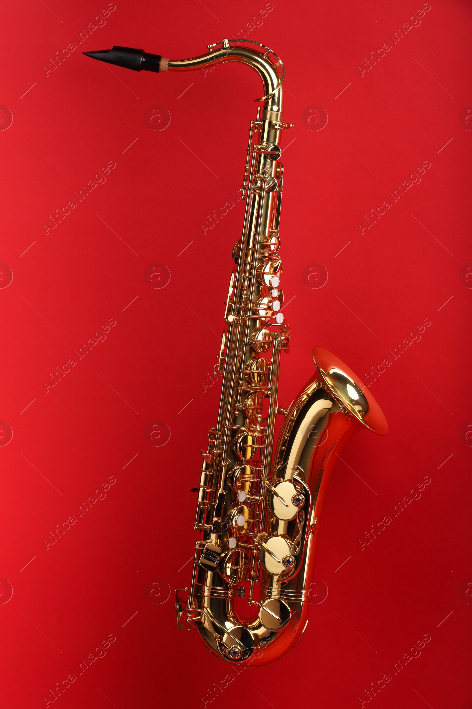 Photo of Jazz. One golden saxophone on red background