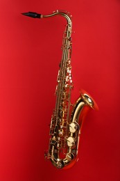 Photo of Jazz. One golden saxophone on red background