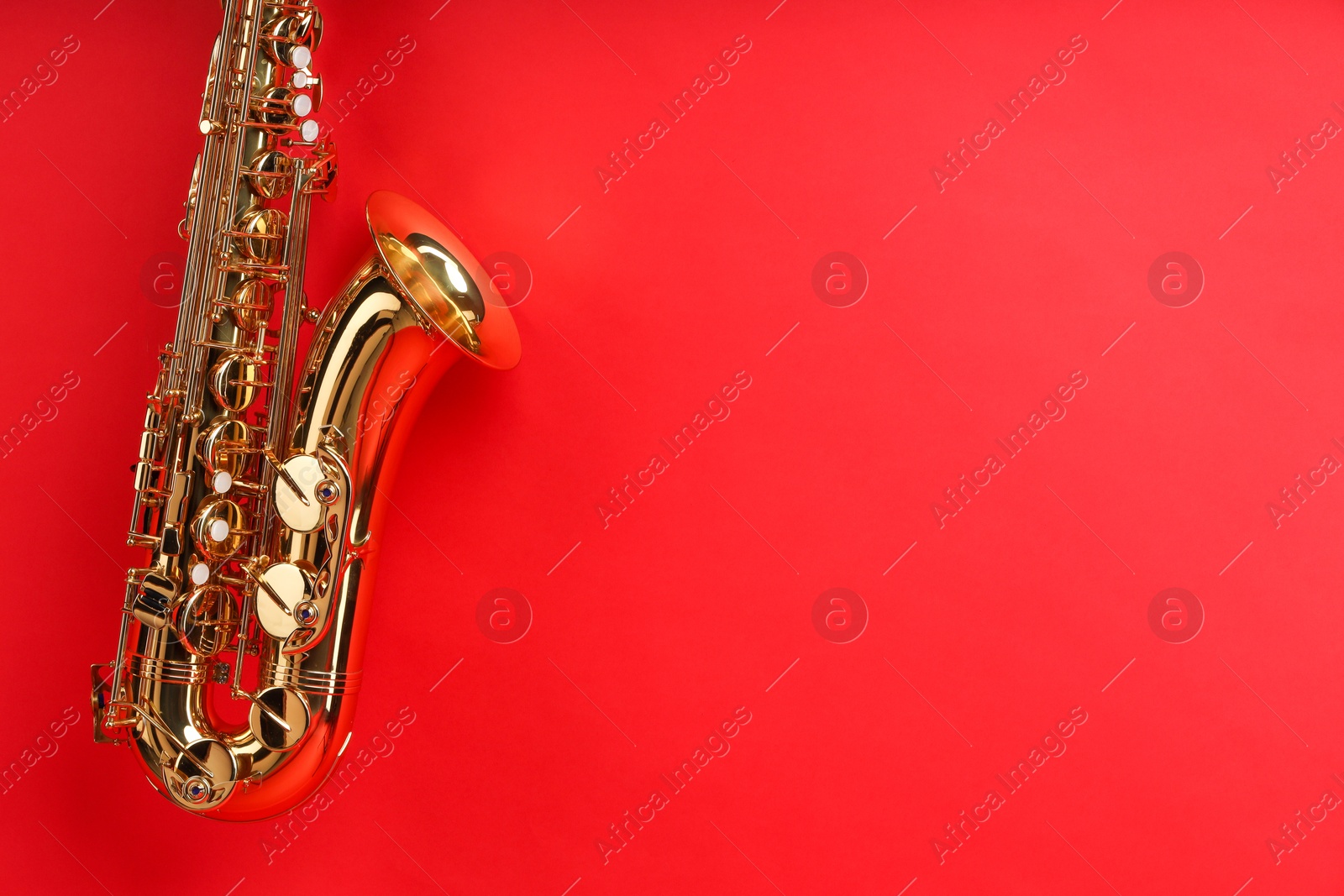 Photo of Jazz. One beautiful saxophone on red background, space for text