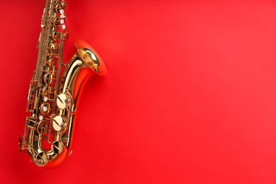 Photo of Jazz. One beautiful saxophone on red background, space for text