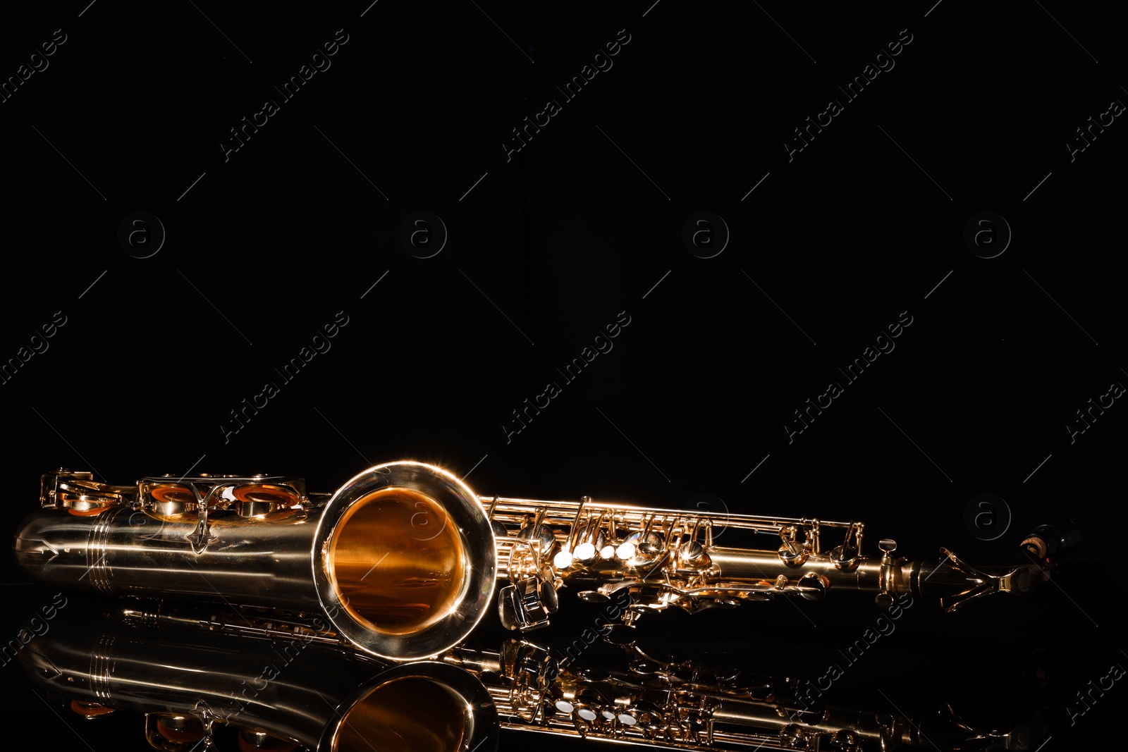 Photo of Jazz. One saxophone on mirror surface against black background, space for text