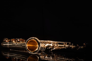 Photo of Jazz. One saxophone on mirror surface against black background, space for text