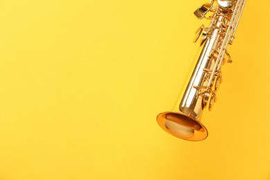 Golden soprano saxophone on yellow background, closeup. Space for text