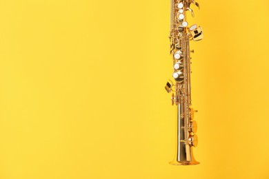 Photo of Golden soprano saxophone on yellow background, closeup. Space for text