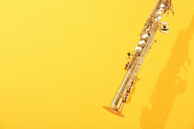 Photo of Golden soprano saxophone on yellow background. Space for text