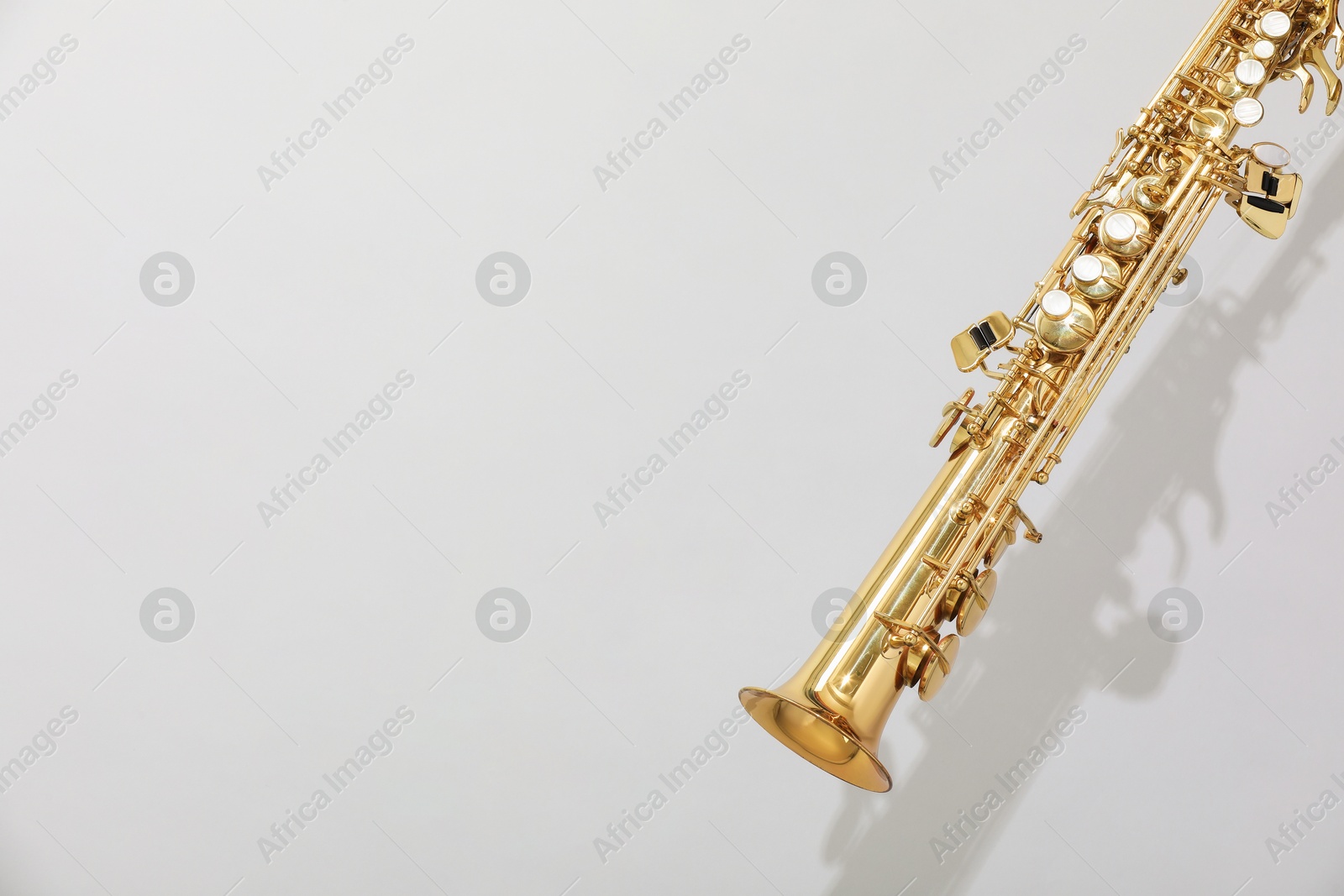 Photo of Golden soprano saxophone on light grey background. Space for text