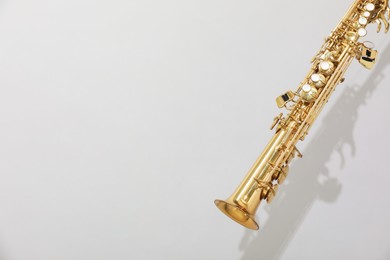 Golden soprano saxophone on light grey background. Space for text