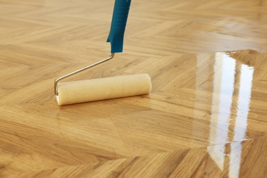 Photo of Polishing parquet with roller and varnish indoors, closeup. Space for text