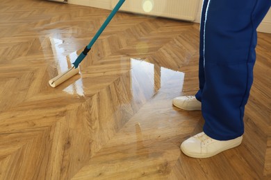 Man polishing parquet with varnish indoors, closeup