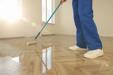 Man polishing parquet with varnish indoors, closeup