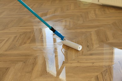 Polishing parquet with roller and varnish indoors, closeup