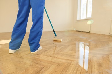 Photo of Man polishing parquet with varnish indoors, closeup. Space for text