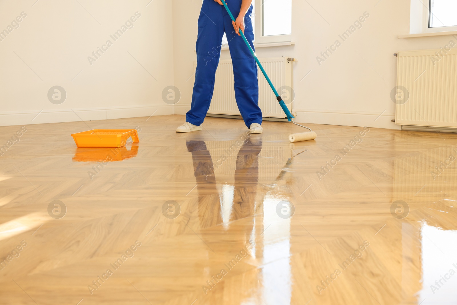 Photo of Man polishing parquet with varnish indoors, closeup