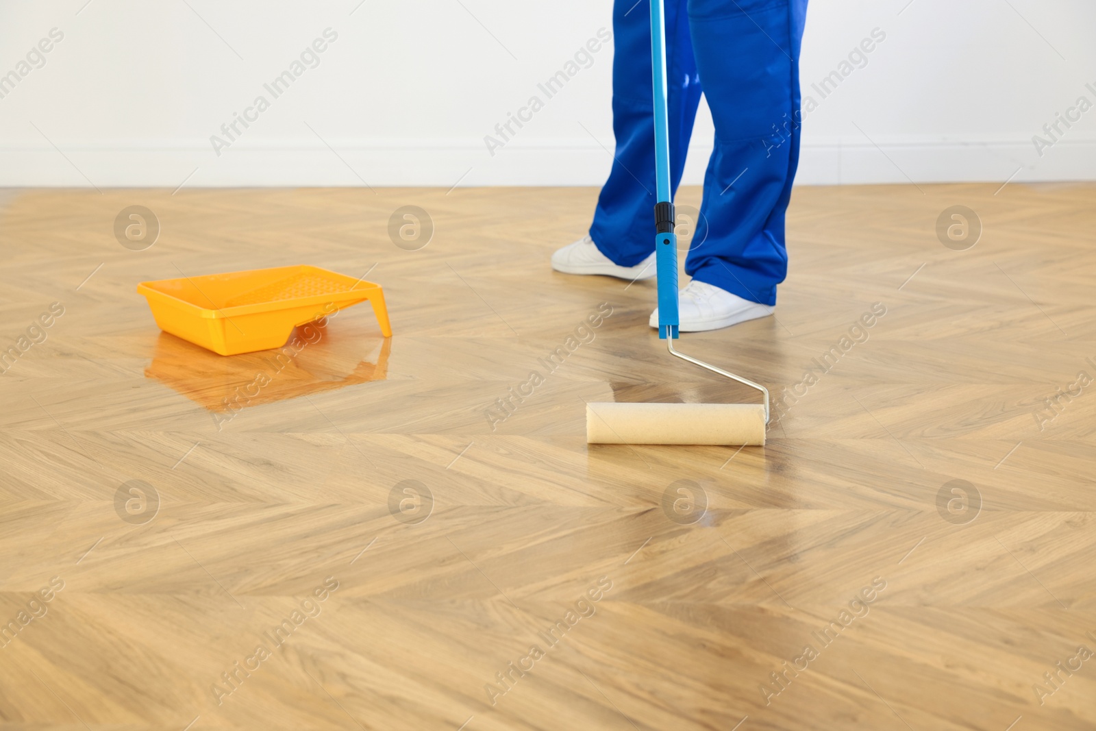 Photo of Man polishing parquet with varnish indoors, closeup