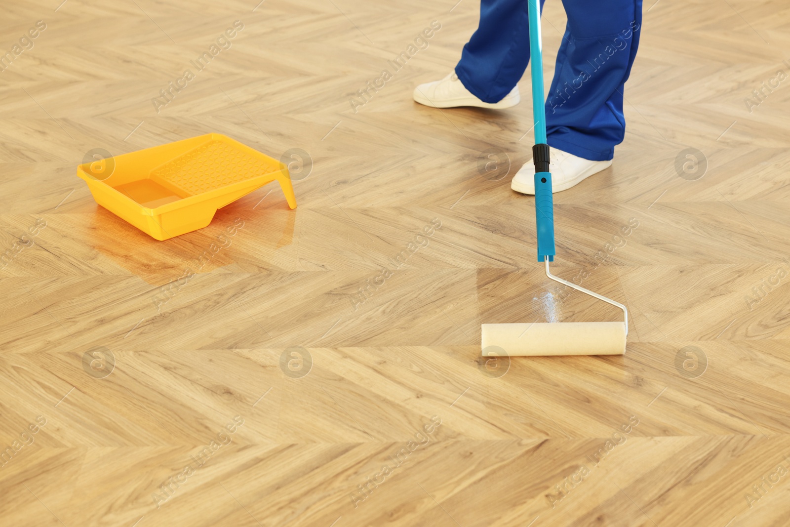 Photo of Man polishing parquet with varnish indoors, closeup