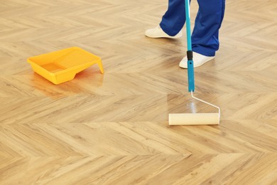 Man polishing parquet with varnish indoors, closeup