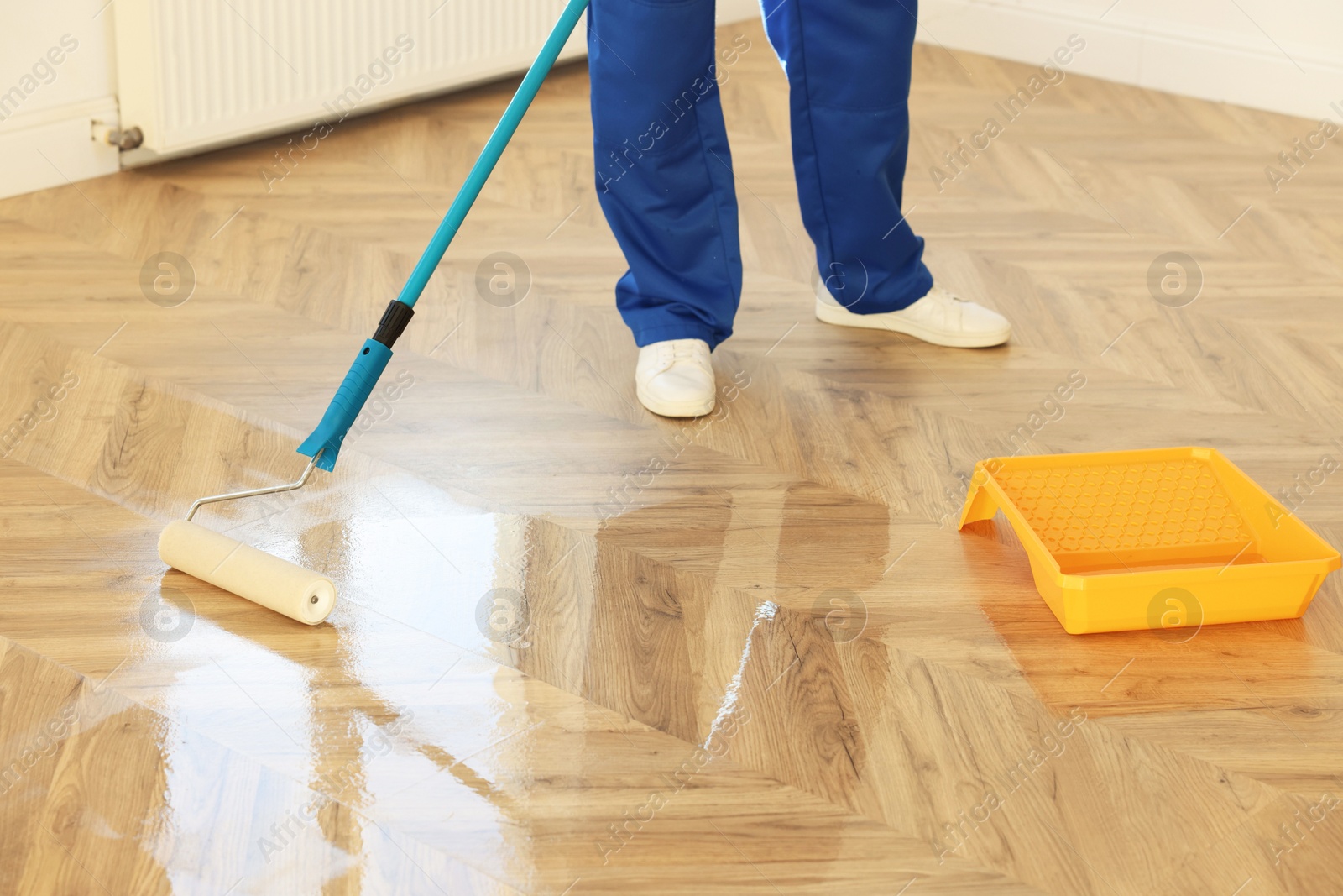 Photo of Man polishing parquet with varnish indoors, closeup