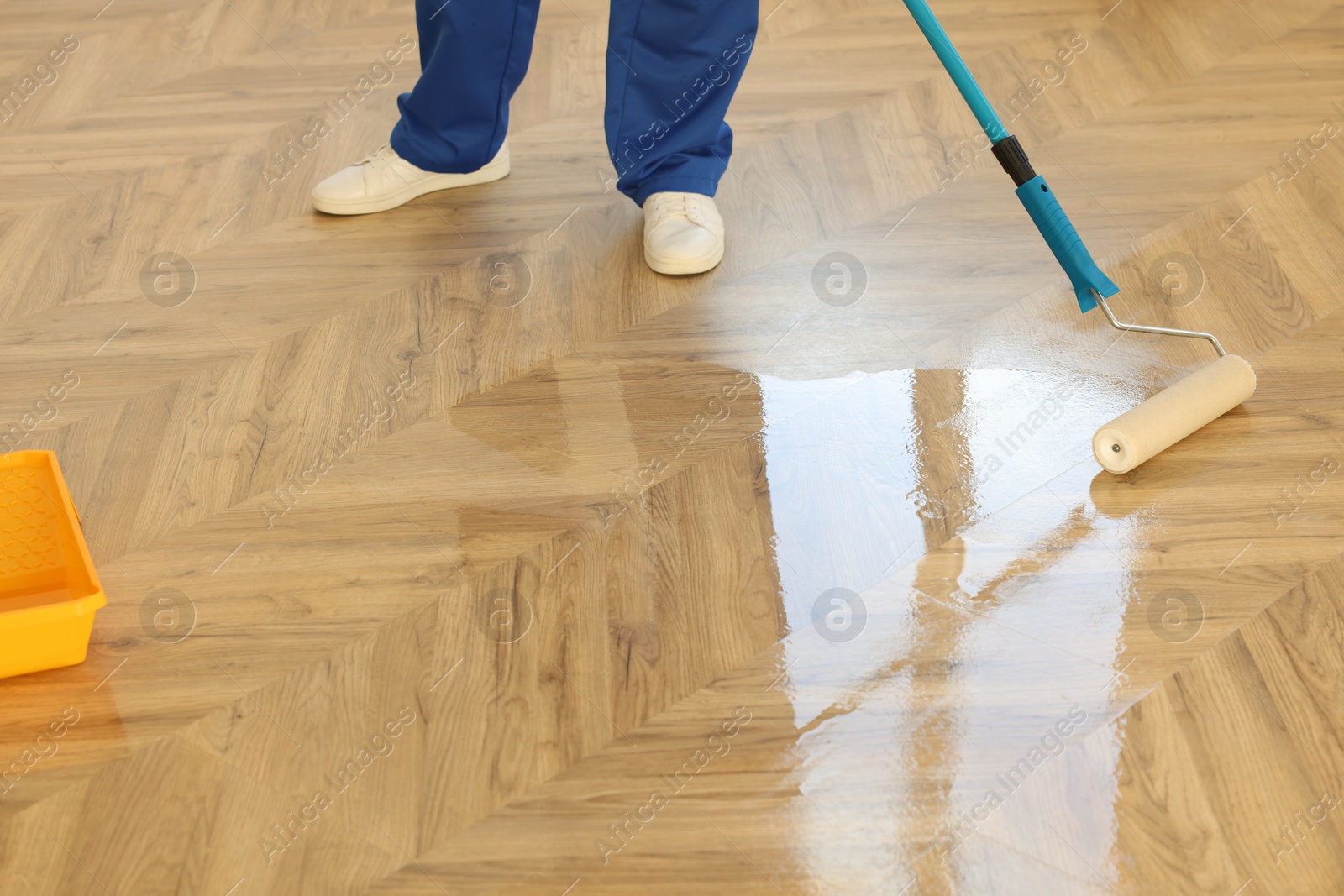 Photo of Man polishing parquet with varnish indoors, closeup