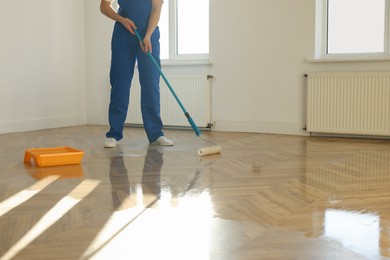 Photo of Man polishing parquet with varnish indoors, closeup