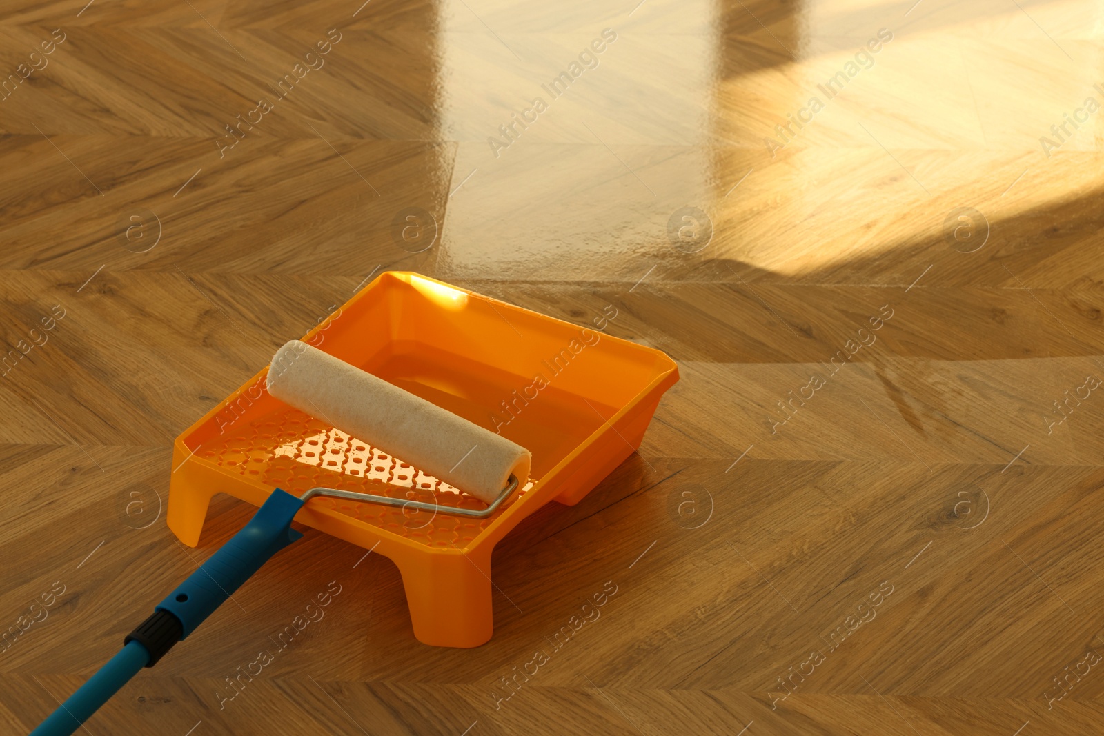 Photo of Process of polishing. Roller and tray with varnish on floor, space for text