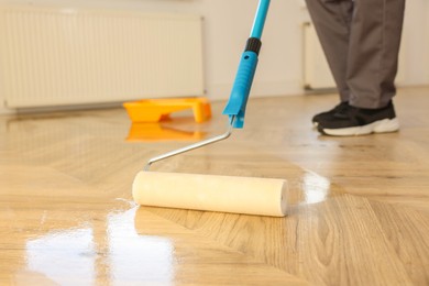 Man polishing parquet with varnish indoors, closeup