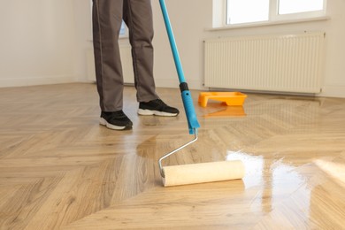 Man polishing parquet with varnish indoors, closeup