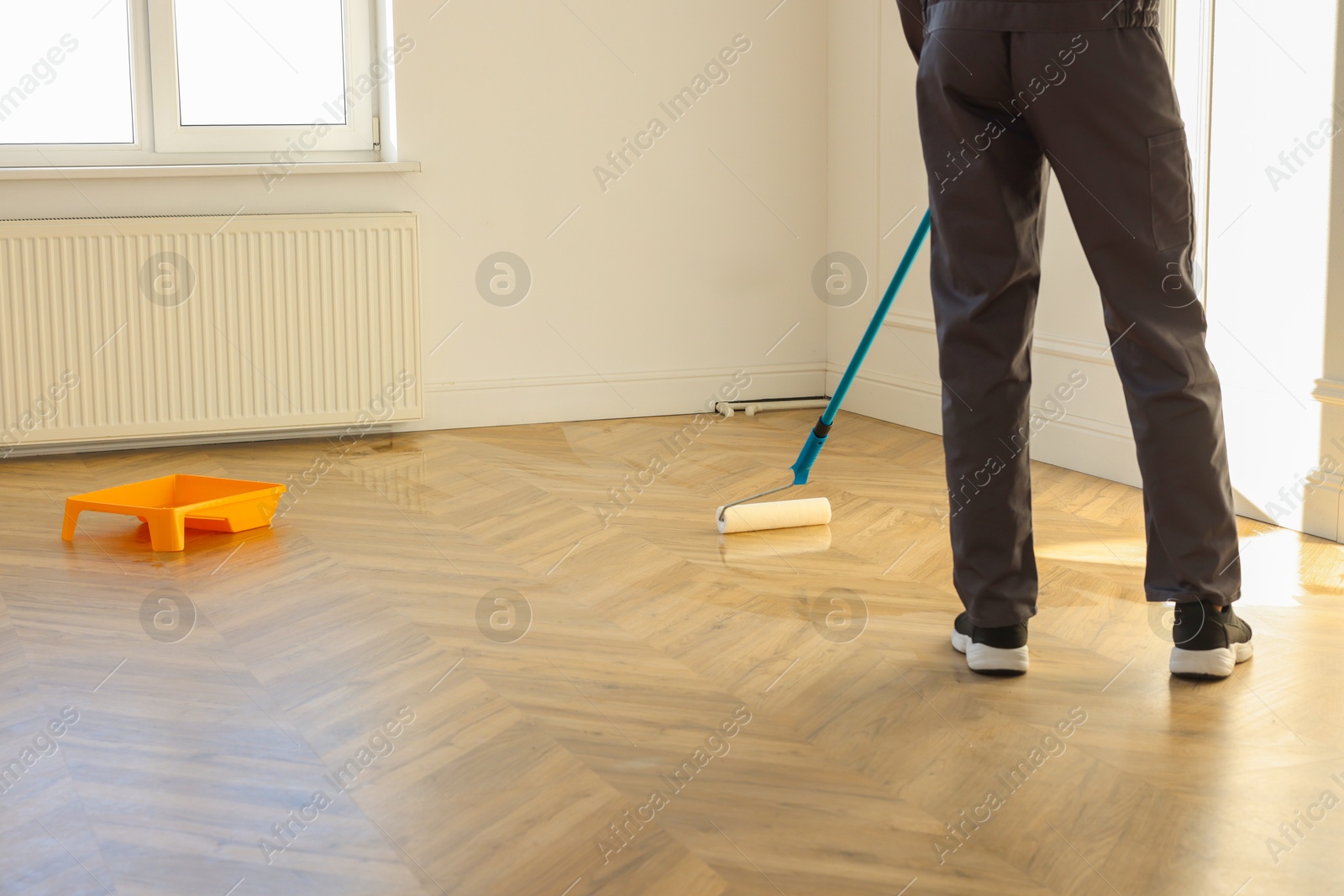 Photo of Man polishing parquet with varnish indoors, closeup