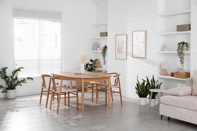 Photo of Stylish wooden table with chairs and decor indoors. Interior design