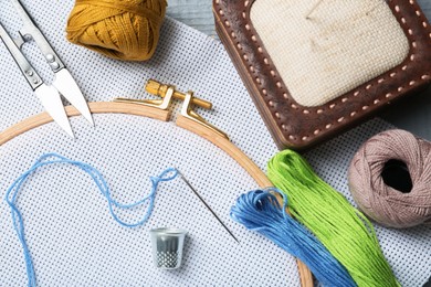 Photo of Different sewing supplies for embroidery on grey wooden table, flat lay