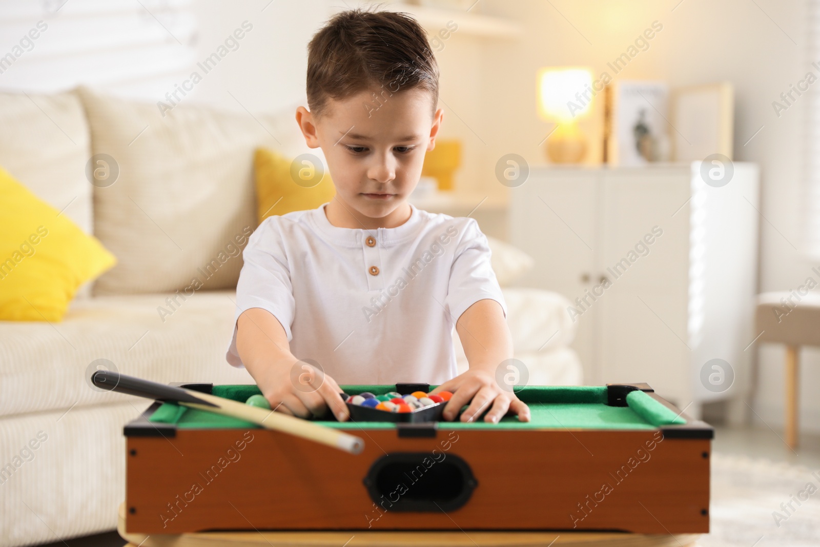 Photo of Cute little boy playing billiards at home