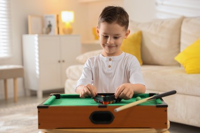 Cute little boy playing billiards at home