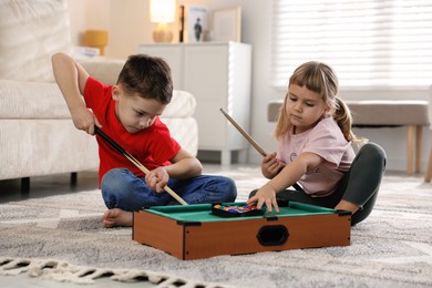 Photo of Cute brother and sister playing billiards at home