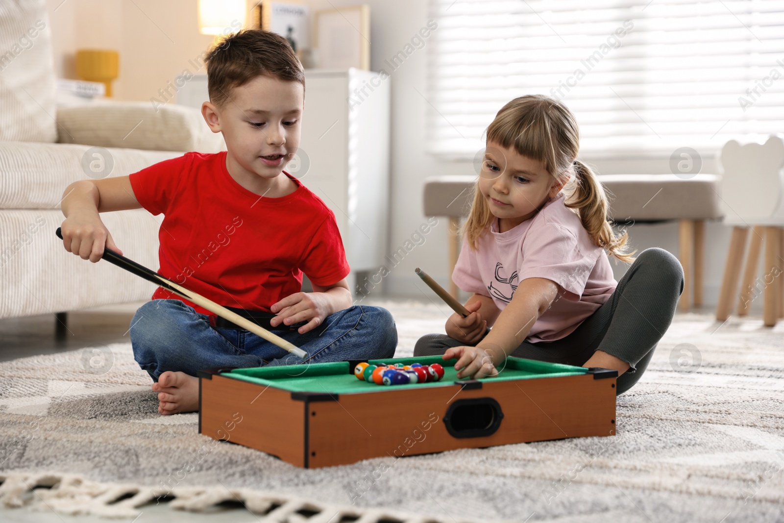 Photo of Cute brother and sister playing billiards at home