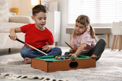 Cute brother and sister playing billiards at home