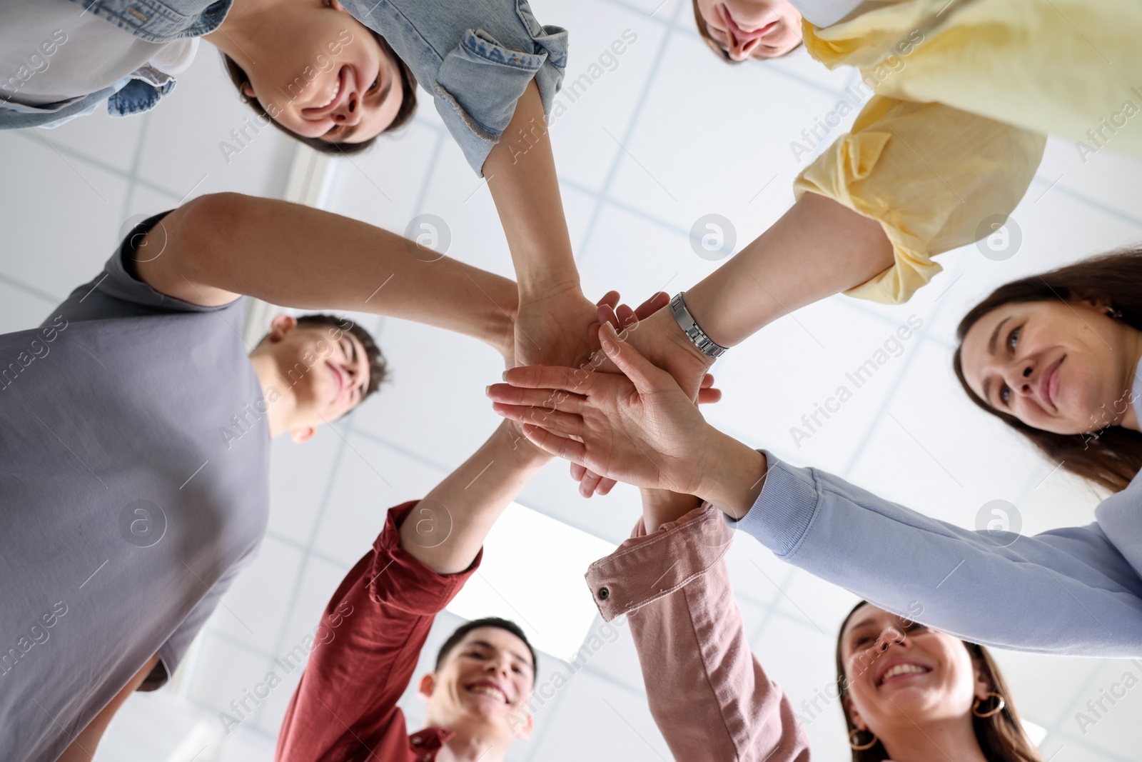 Photo of Unity concept. People holding hands together indoors, bottom view