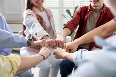 Photo of Unity concept. People holding fists together indoors, closeup