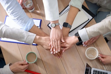 Unity concept. People holding hands together above wooden table, top view