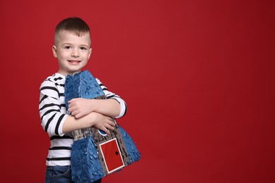 Photo of Happy boy with rocket shaped pinata on red background. Space for text