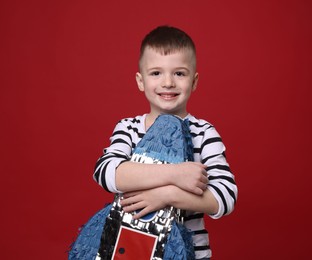 Happy boy with rocket shaped pinata on red background