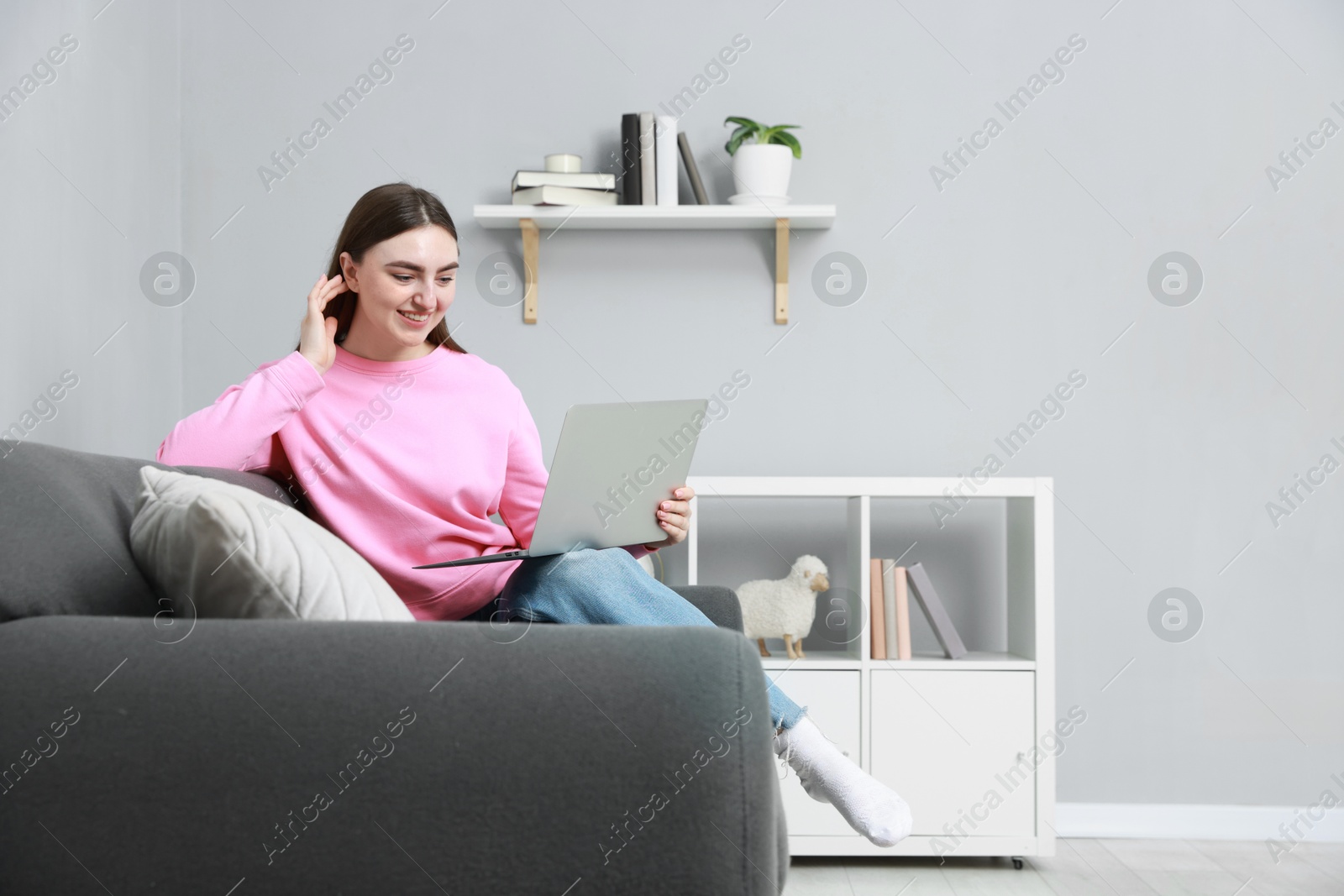 Photo of Smiling young woman working on laptop at home