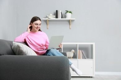 Photo of Smiling young woman working on laptop at home