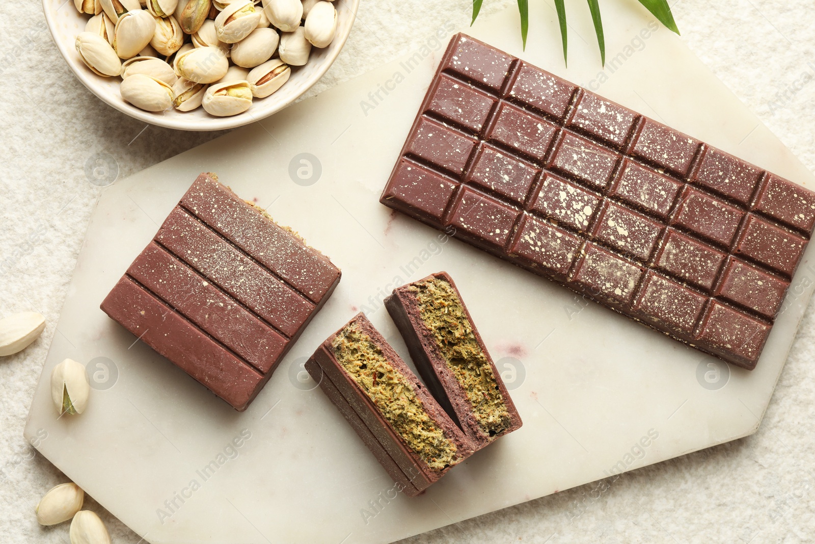 Delicious Dubai chocolate with pistachios and knafeh on light textured table, flat lay Photo of Delicious Dubai chocolate with pistachios and knafeh on light textured table, flat lay