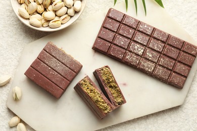 Photo of Delicious Dubai chocolate with pistachios and knafeh on light textured table, flat lay