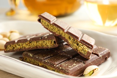 Photo of Pieces of delicious Dubai chocolate with pistachios and knafeh on table, closeup